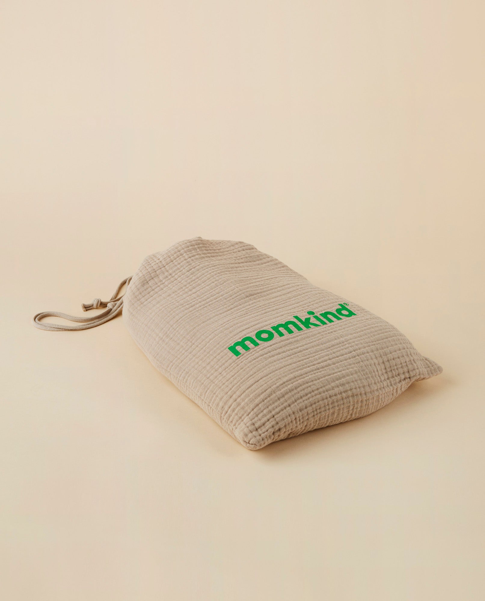 Billede af momkind kind robe som er omgivet af dens indpakning i bomuld. Der er et grønt momkind logo på.