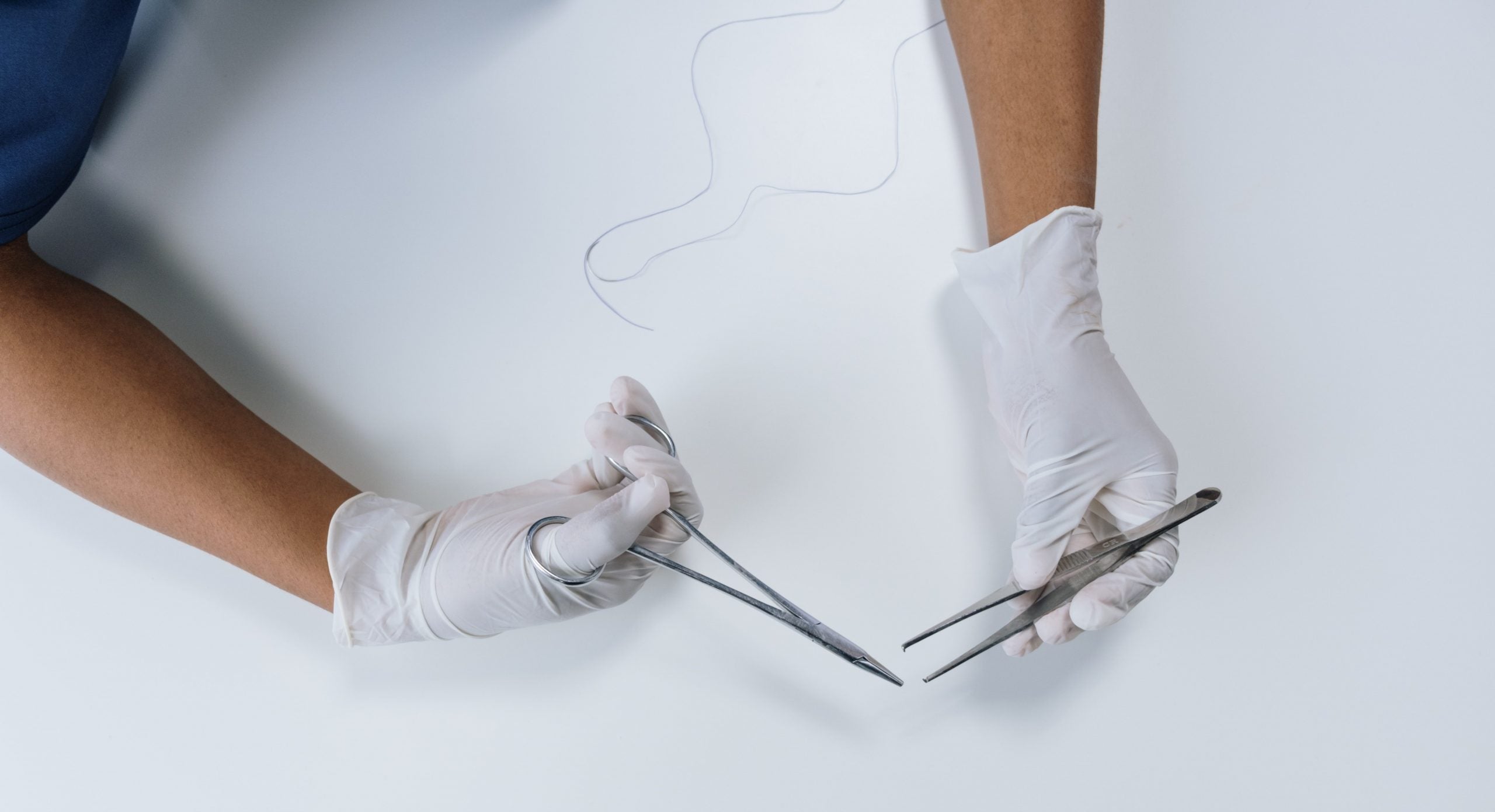 syning af bristning efter fødsel to hænder med plastikhandsker der holder en saks og en pincet