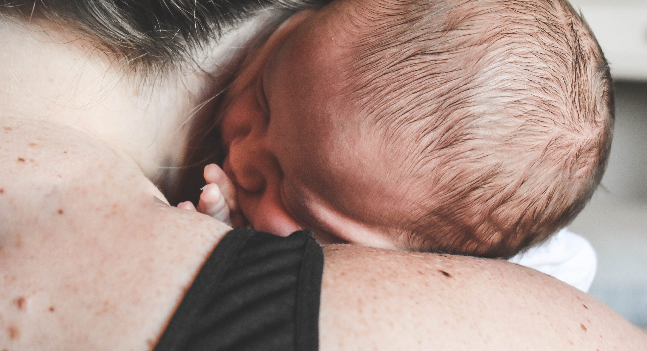 fystioterapeutens tips til træning efter kejsersnit kvinde holder nyfødt baby over skulderen