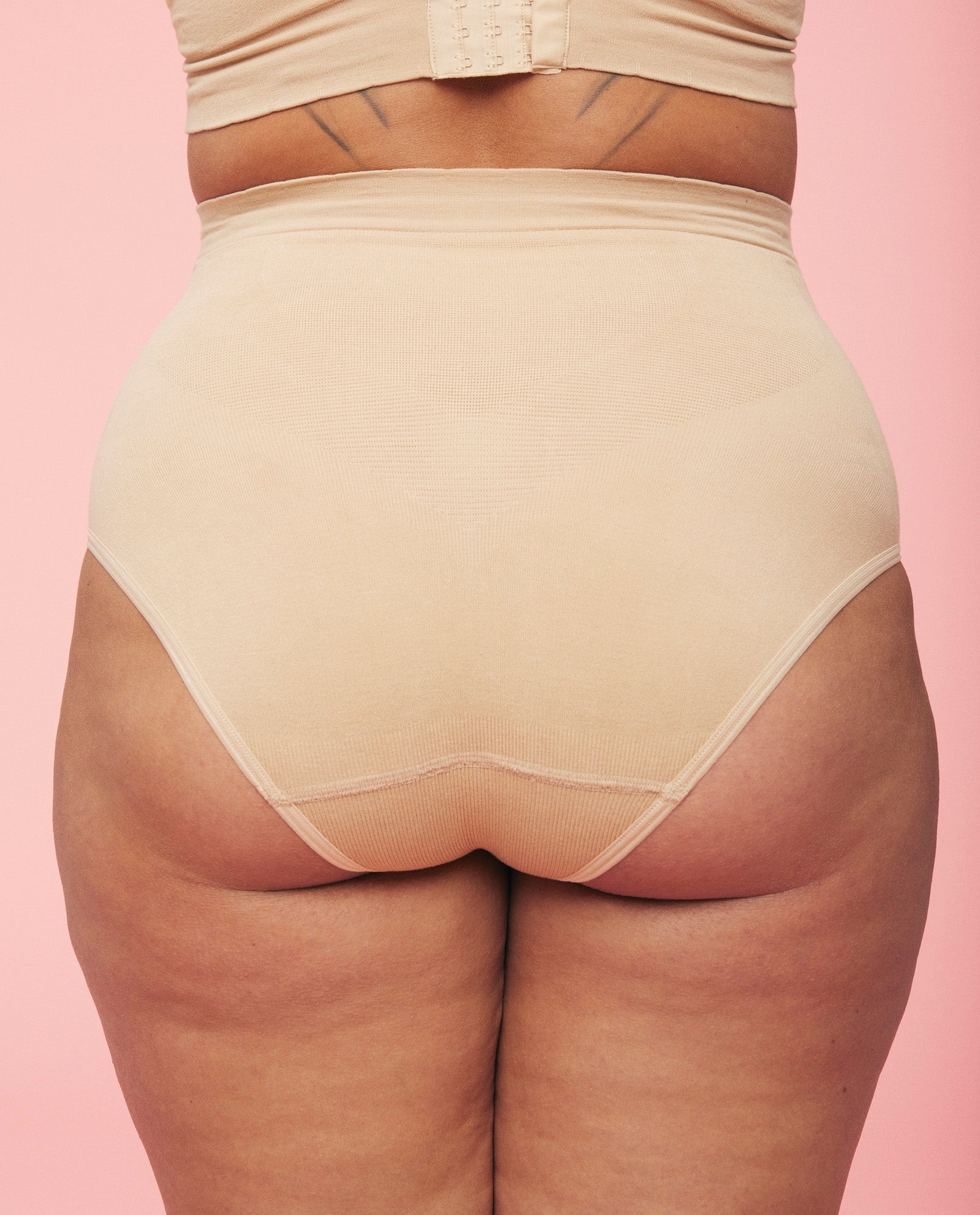 Billede af kvindes bagdel iført momkinds belly support graviditetstrusser i sand