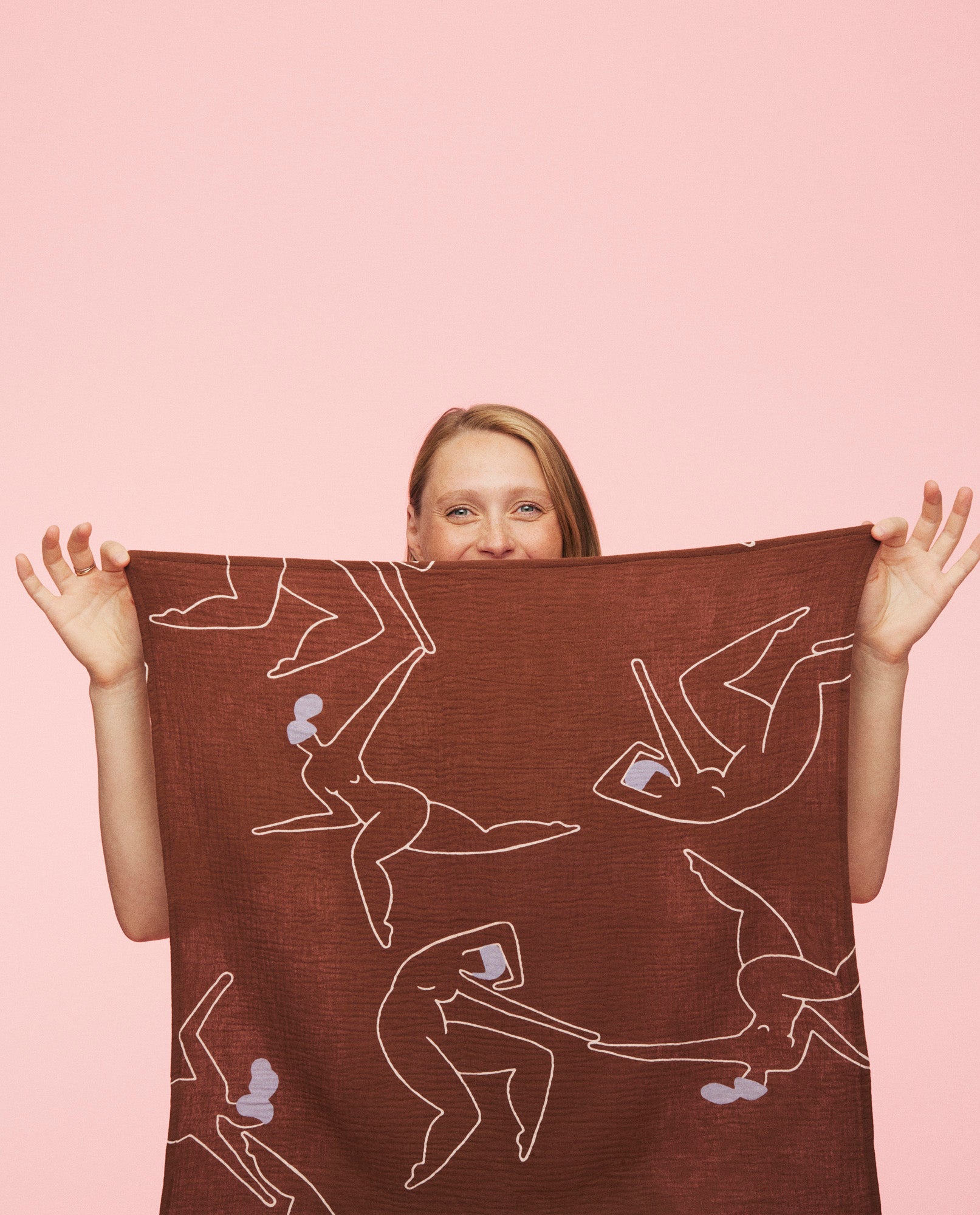 kvinde holder brun stofble med mønster fra momkind op foran sig