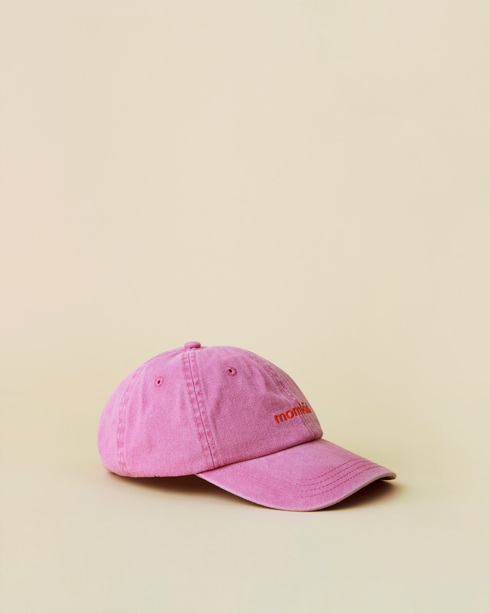 Momkind cap I lyseroed og roed logo. Cap ses fra siden.