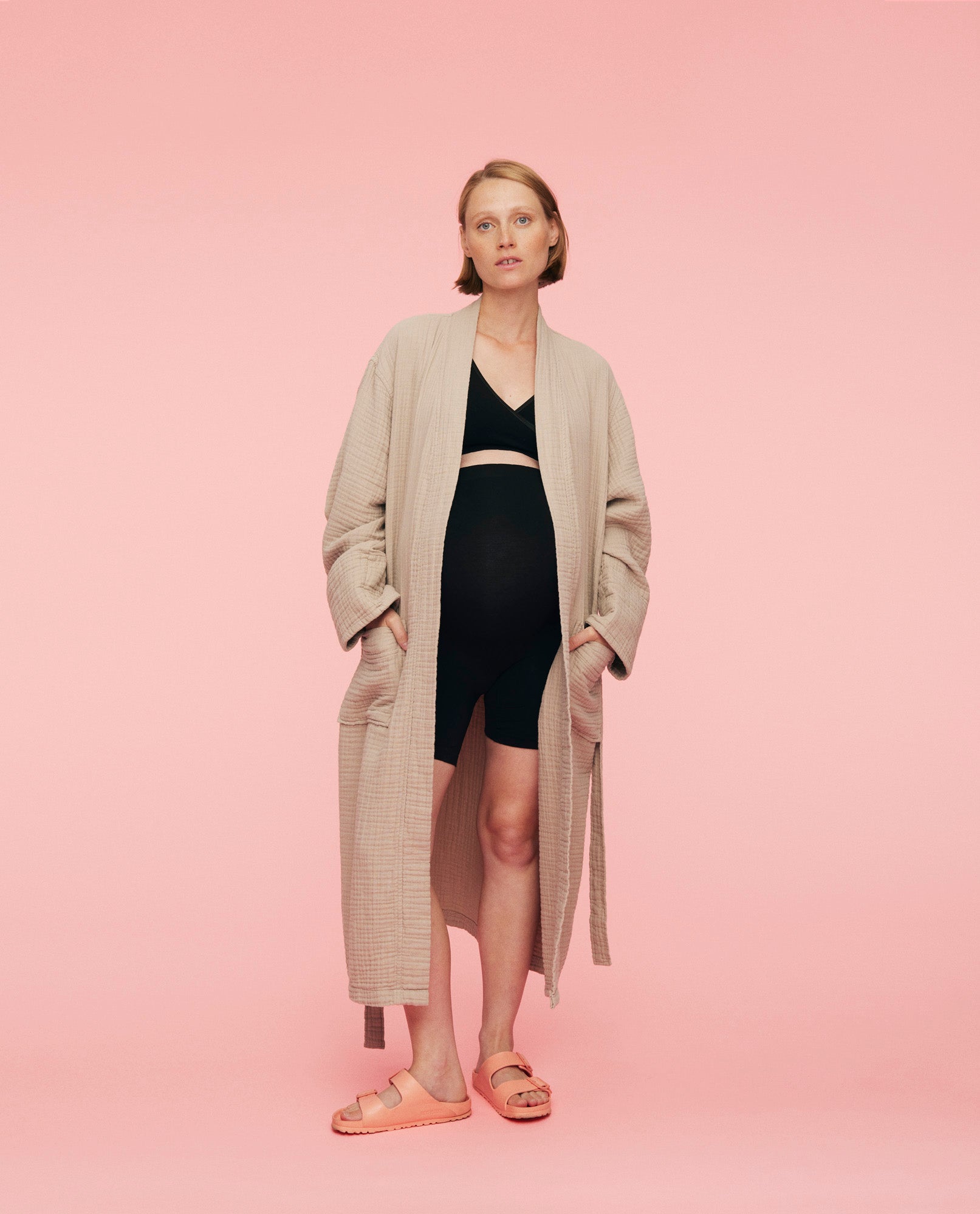 Kvinde iført momkind kind robe. Morgenkåben er åben og hun holder sine hænder i kåbens lommer.