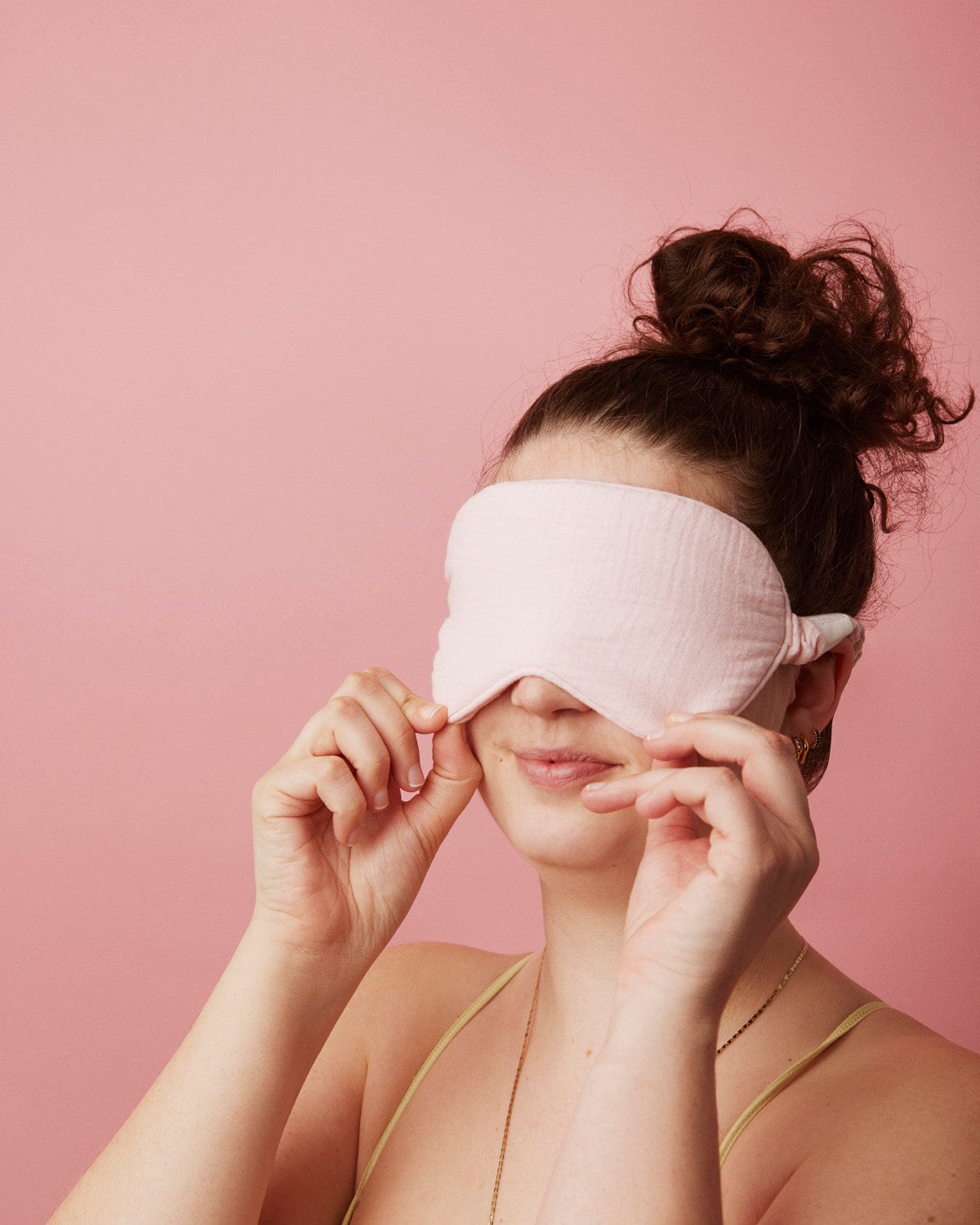 Sovemaske fra momkind i lyseroed, ses på en model som har den på øjnene.