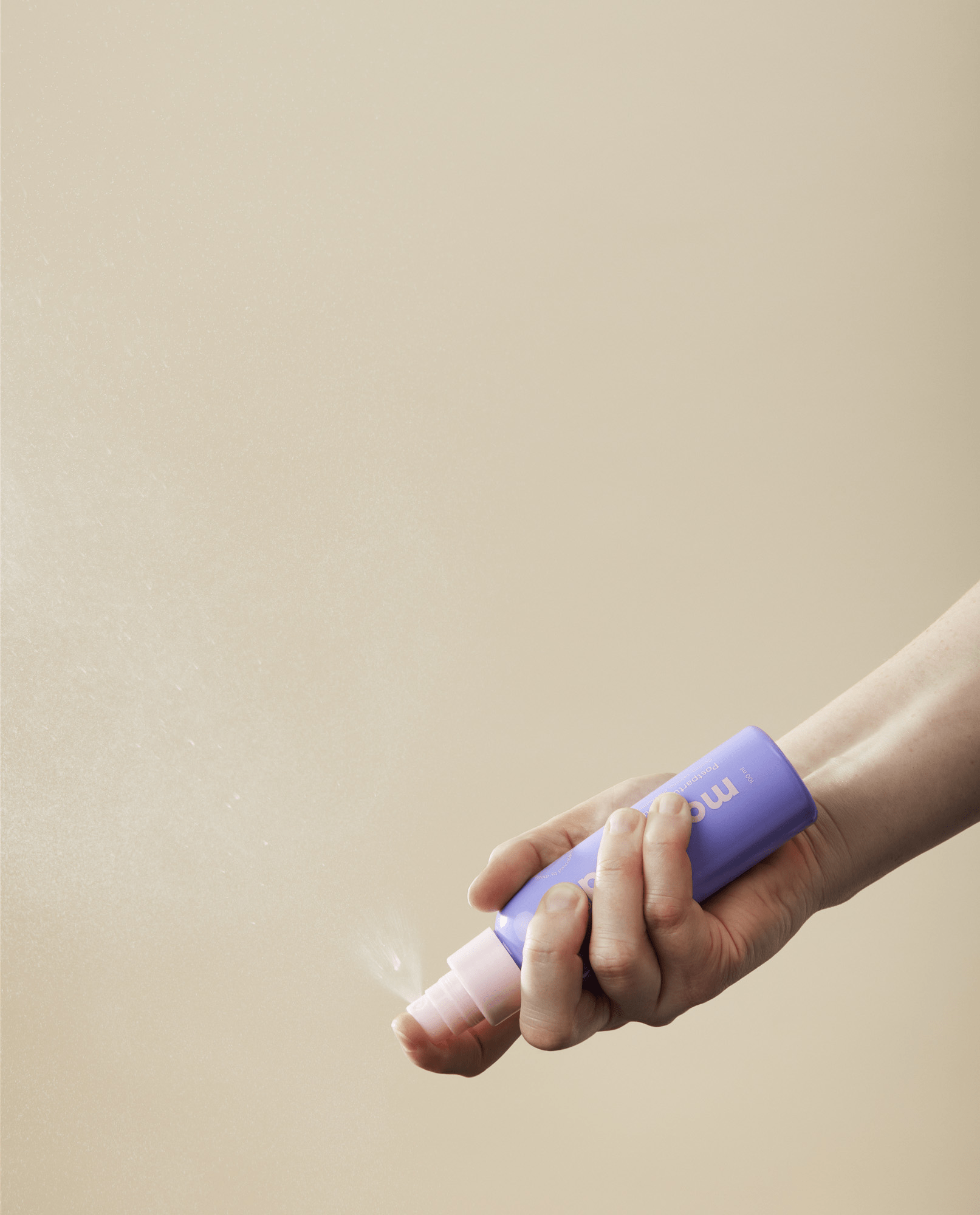 kvinde holder momkind postpartum serum mist til efter fødslen i hånden og viser sprayfunktion