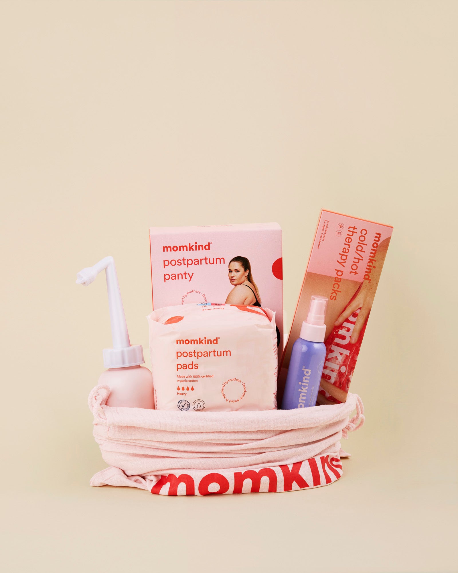 Momkind mellem efterfoedselspakke. Posen indeholder skylleflaske, etferfoedselsbind, efterfoedselstrusser, postpartum serum mist og køle/varme pose. 