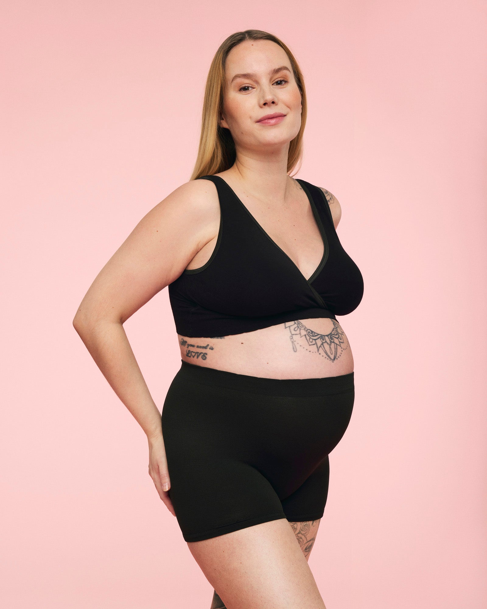 gravid kvinde iført momkind efterfødselstrusse og crossover bh i sort 