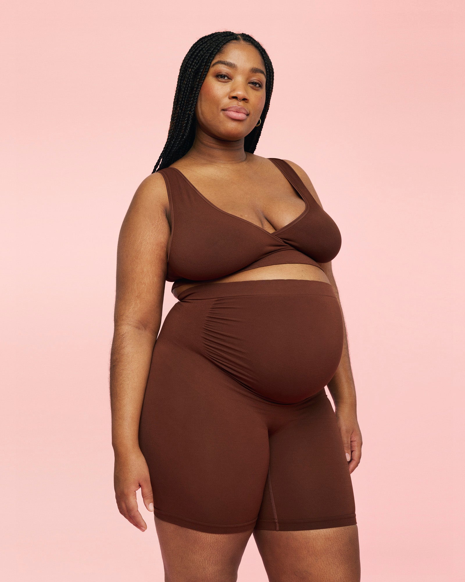 gravid kvinde står op og smiler iført brune momkind gravid shorts og crossover ammebh i farven chocolate 