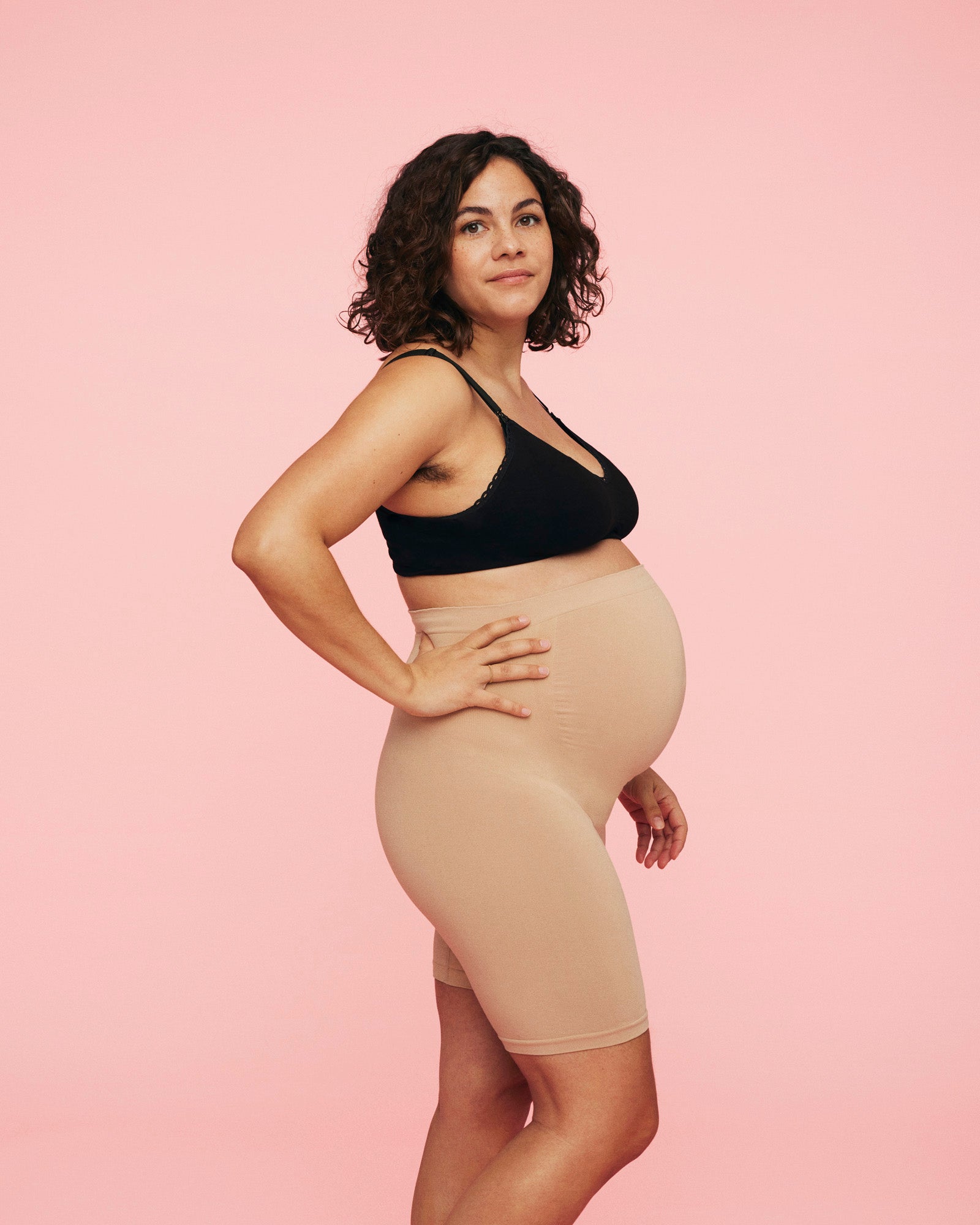 gravid kvinde iført sort amme bh fra momkind og gravid shorts i sand