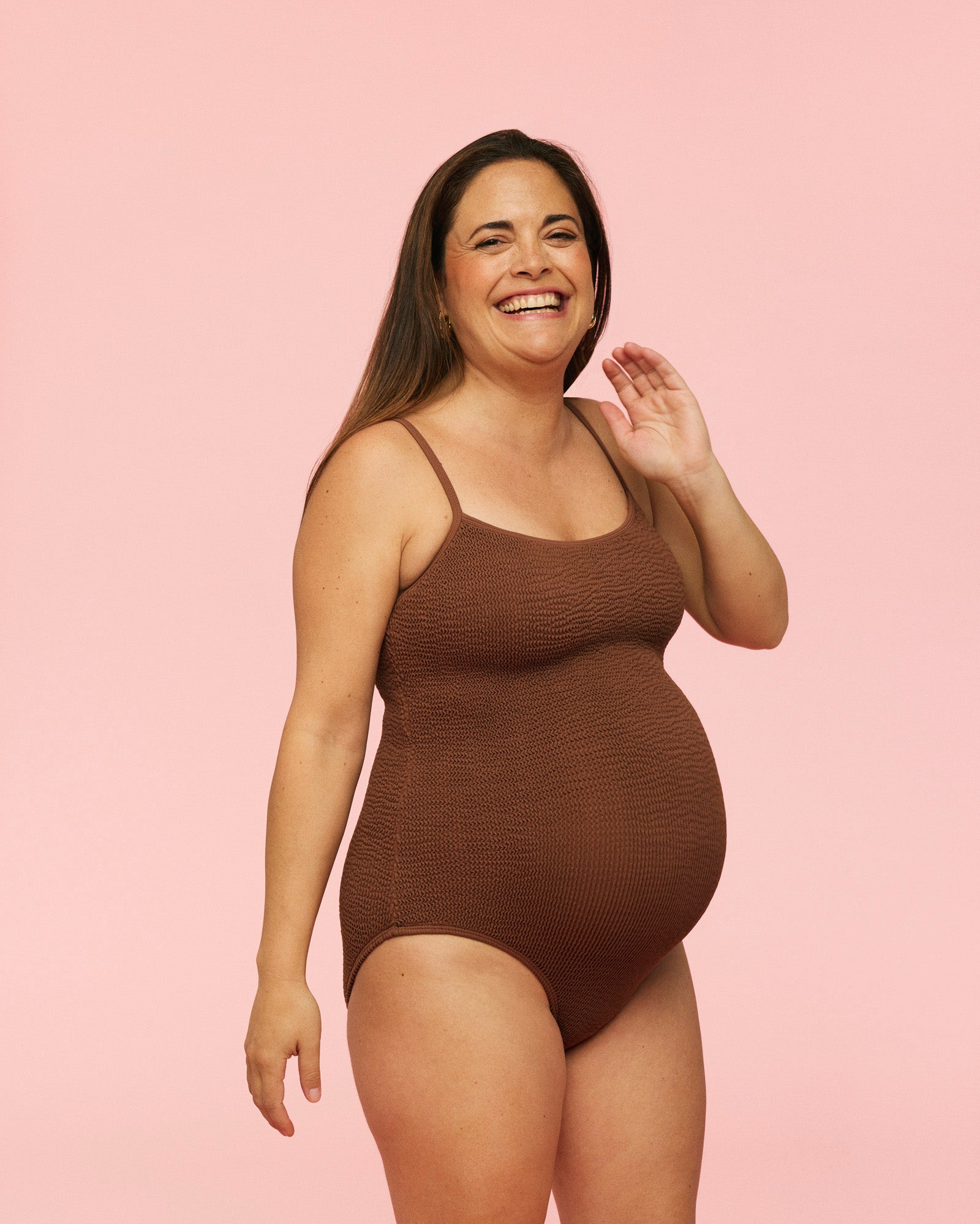 Gravid kvinde som smiler iført Momkind gravid badedragt i farven chocolate / brun.